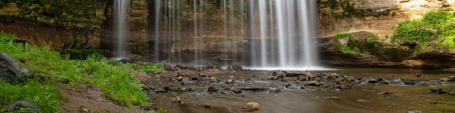 Una cascada que se precipita sobre rocas en un área boscosa.