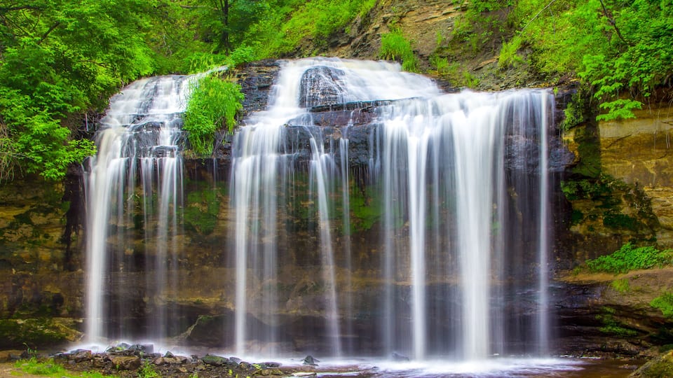 A waterfall cascading over a rocky cliff surrounded by lush greenery.