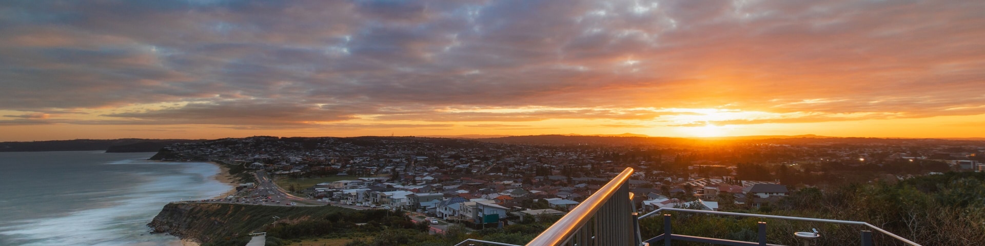 A coastal sunset view with a staircase leading down to the beach.