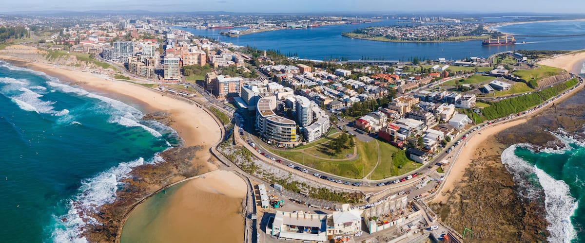 Vista aérea de una ciudad costera con una playa, edificios residenciales y un puerto.