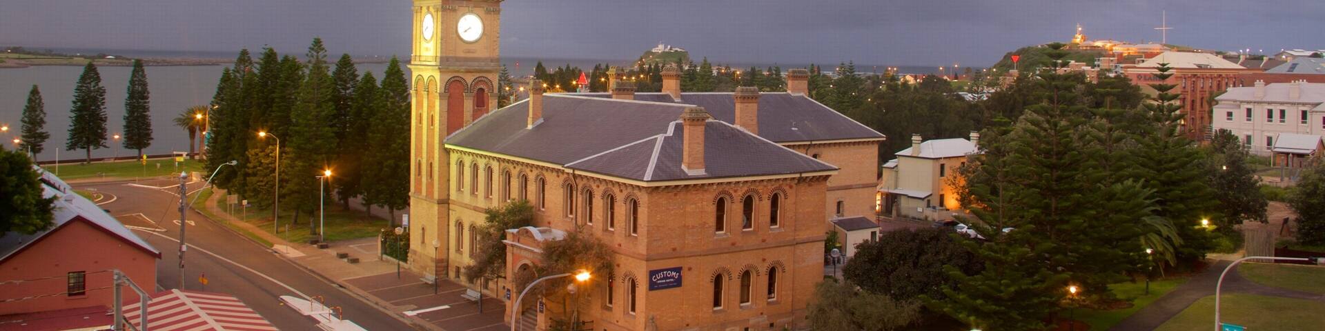 A historic building with a clock tower, a waterfront, and a stormy sky.