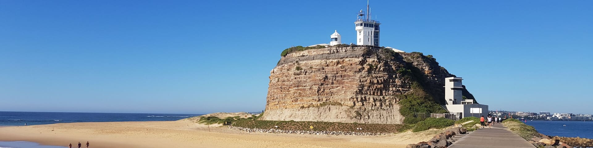 A coastal fort on a cliff overlooking a sandy beach with a clear sky.