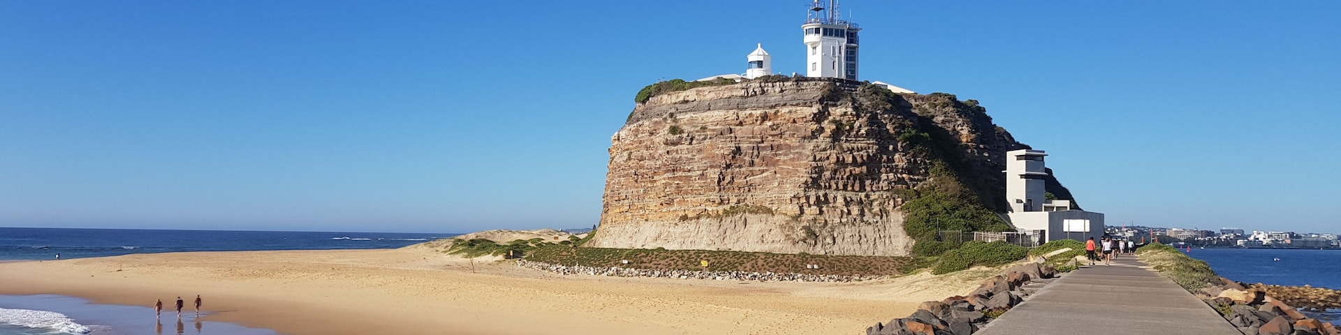 Eine Küstenfestung auf einer Klippe mit Blick auf einen Sandstrand bei klarem Himmel.