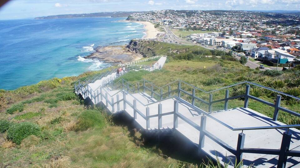 A coastal town with a prominent staircase leading down to the beach, overlooking the ocean.