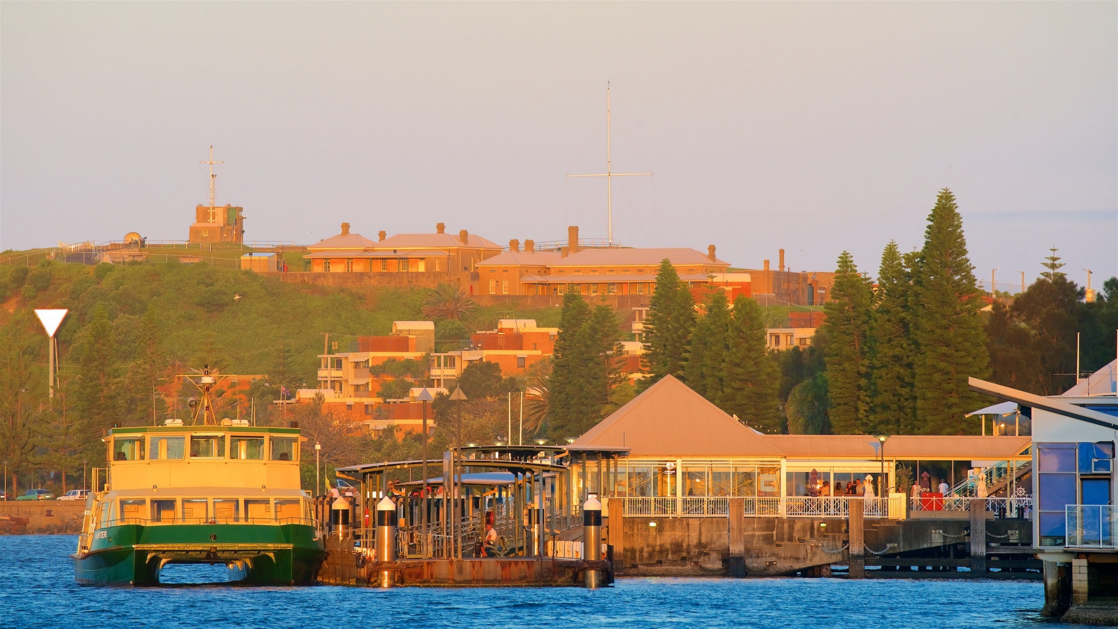 A coastal town with a ferry dock, buildings, and a hill with a church steeple.