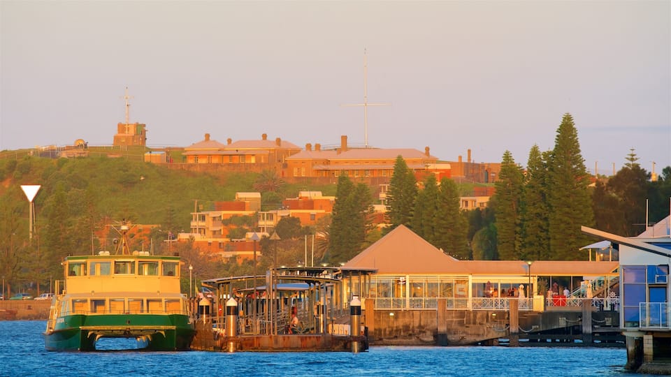 A coastal town with a ferry dock, buildings, and a hill with a church steeple.