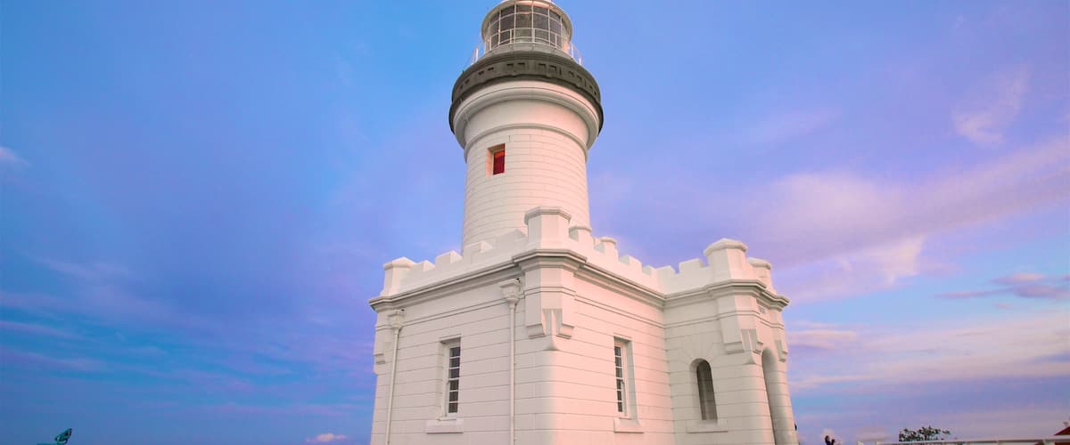 Un faro bianco con base blu, sullo sfondo di un cielo al crepuscolo.