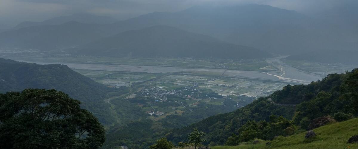 A valley with a river, surrounded by mountains and greenery.