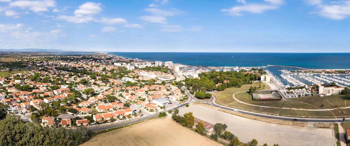 A coastal town with residential areas, a marina, and a beach.