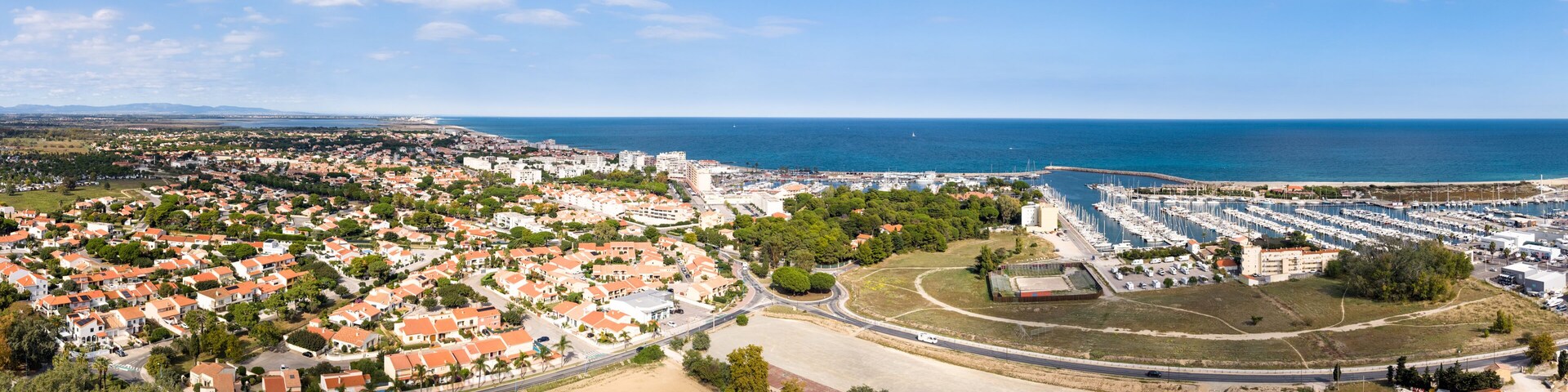 A coastal town with residential areas, a marina, and a beach.