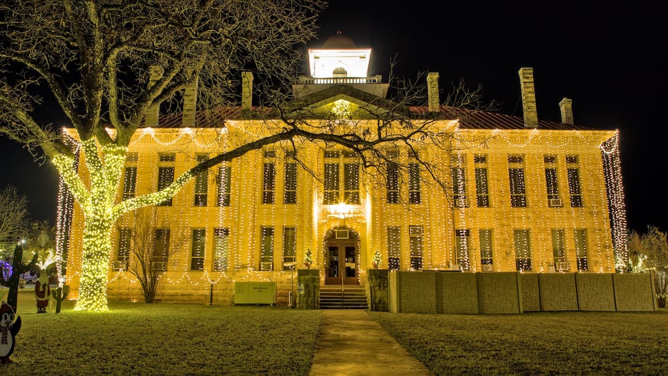 A historic building with a clock tower, adorned with string lights.
