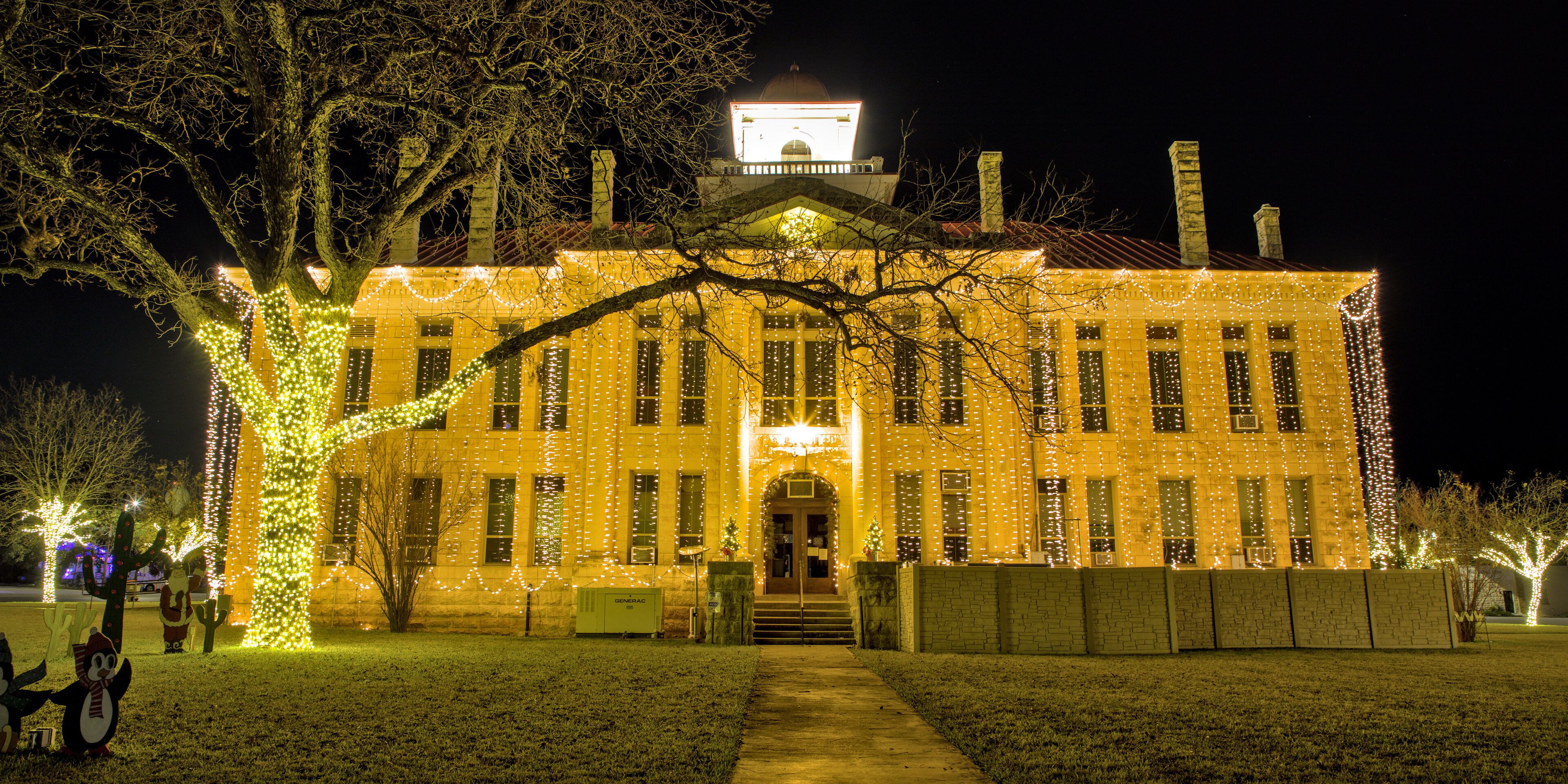 A historic building with a clock tower, adorned with string lights.