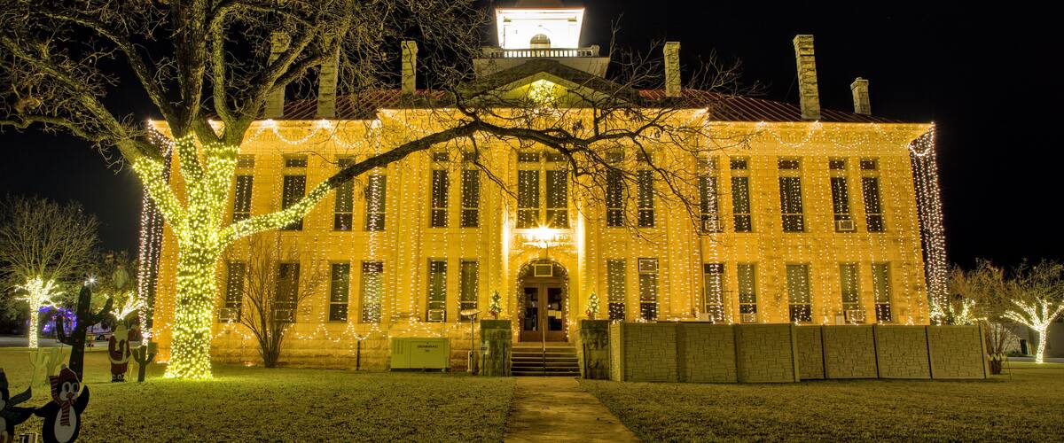 A historic building with a clock tower, adorned with string lights.