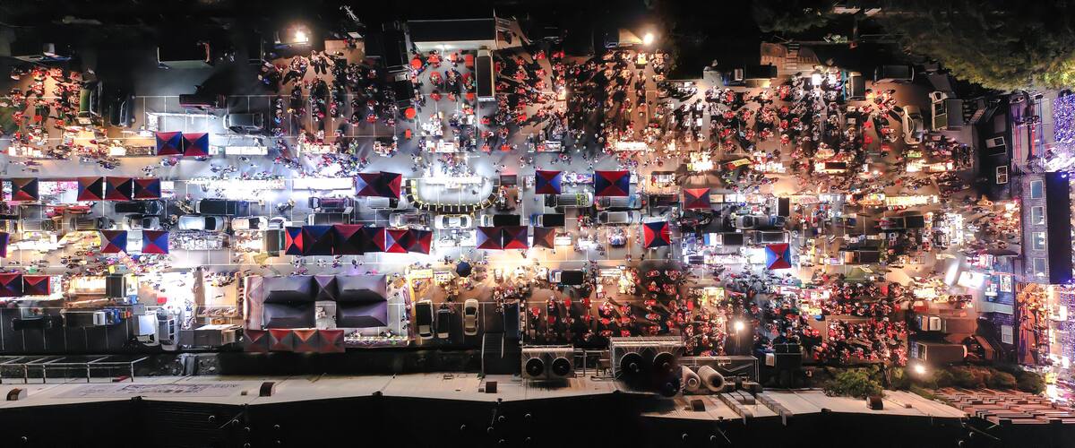 A densely packed outdoor market at night with numerous stalls and bright lights.