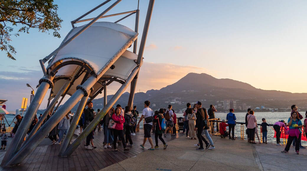 Tamsui which includes a sunset and a bay or harbor as well as a small group of people