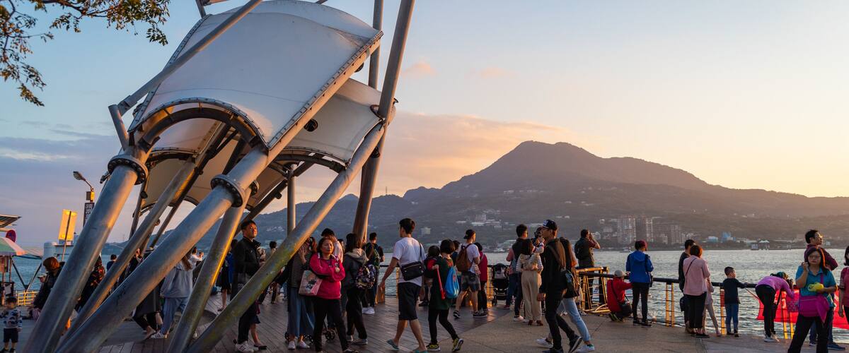 Tamsui which includes a sunset and a bay or harbor as well as a small group of people