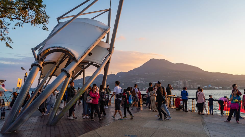 Tamsui which includes a sunset and a bay or harbor as well as a small group of people