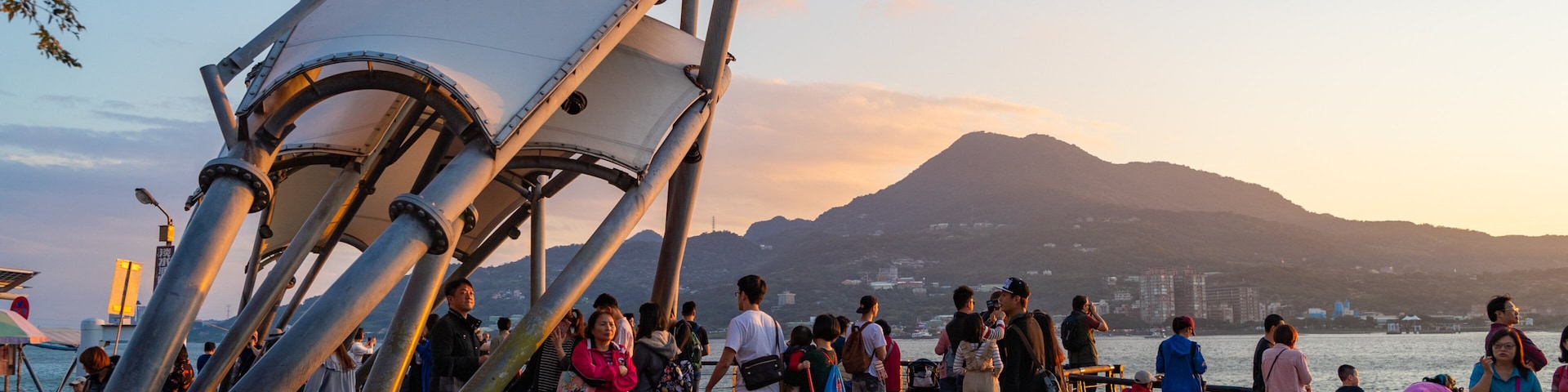 Tamsui which includes a sunset and a bay or harbor as well as a small group of people