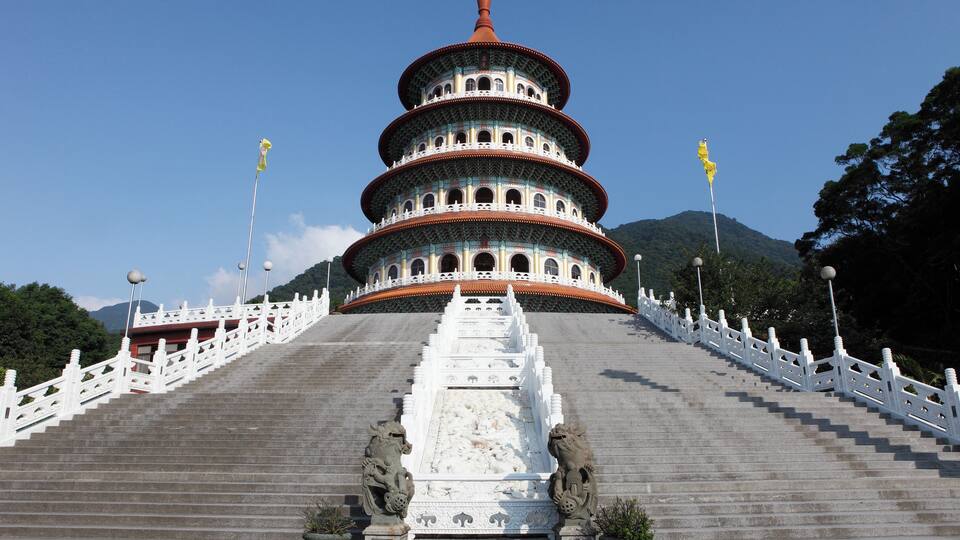 A multi-tiered pagoda with white railings and statues at the base.