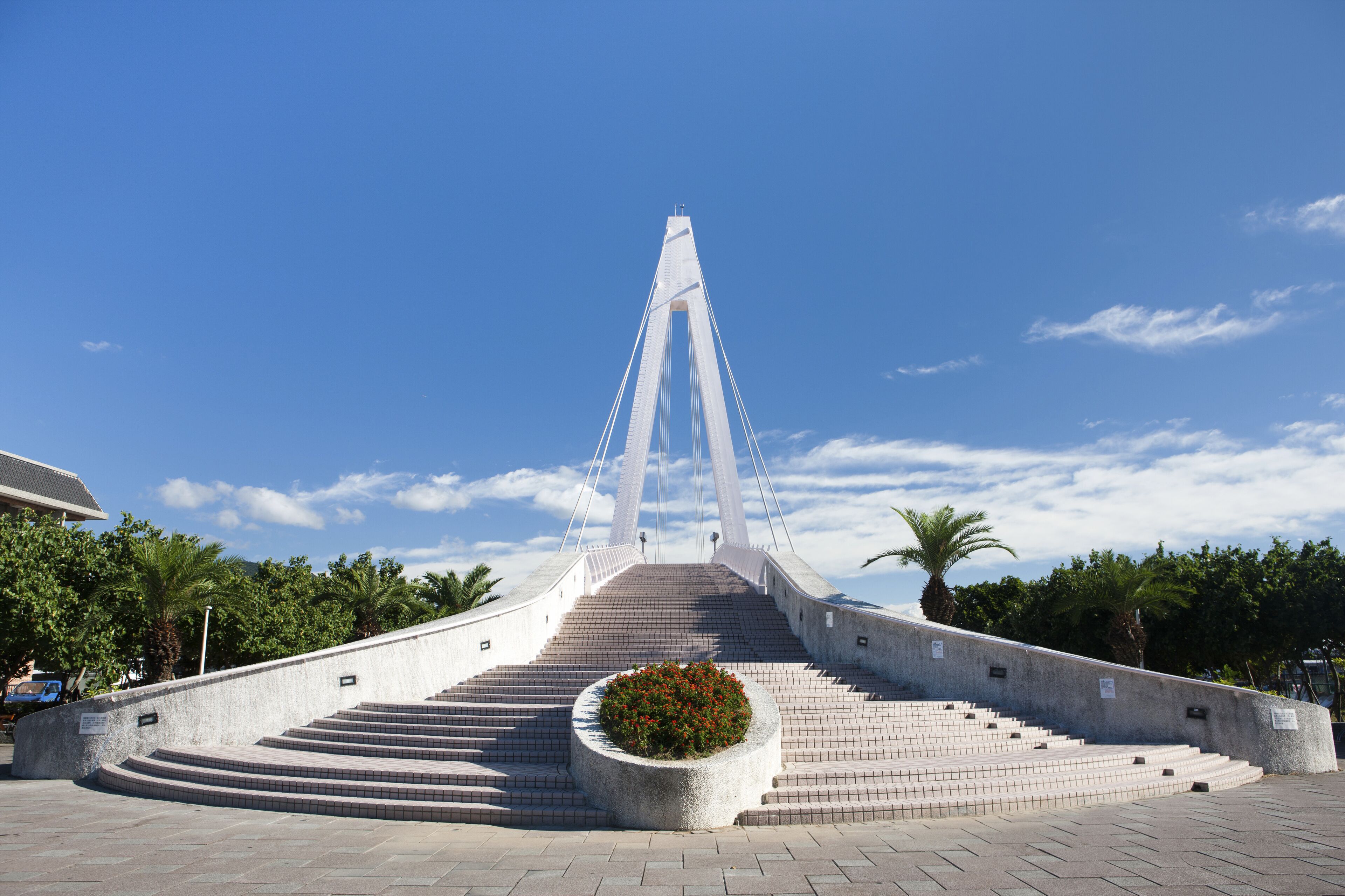 Uma grande ponte com uma torre central e um canteiro circular de flores ao primeiro plano.