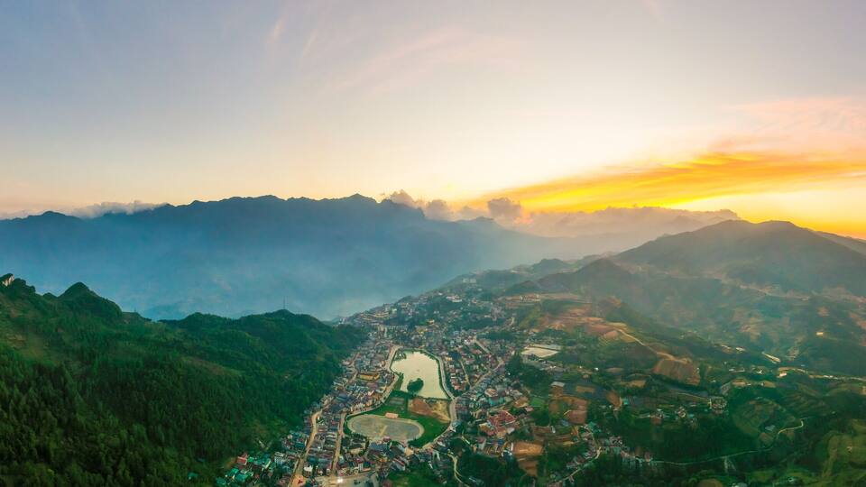 A mountainous landscape with a town nestled in the valley, surrounded by dense forests and a river.