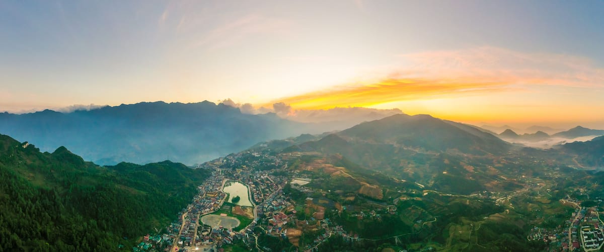 A mountainous landscape with a town nestled in the valley, surrounded by dense forests and a river.