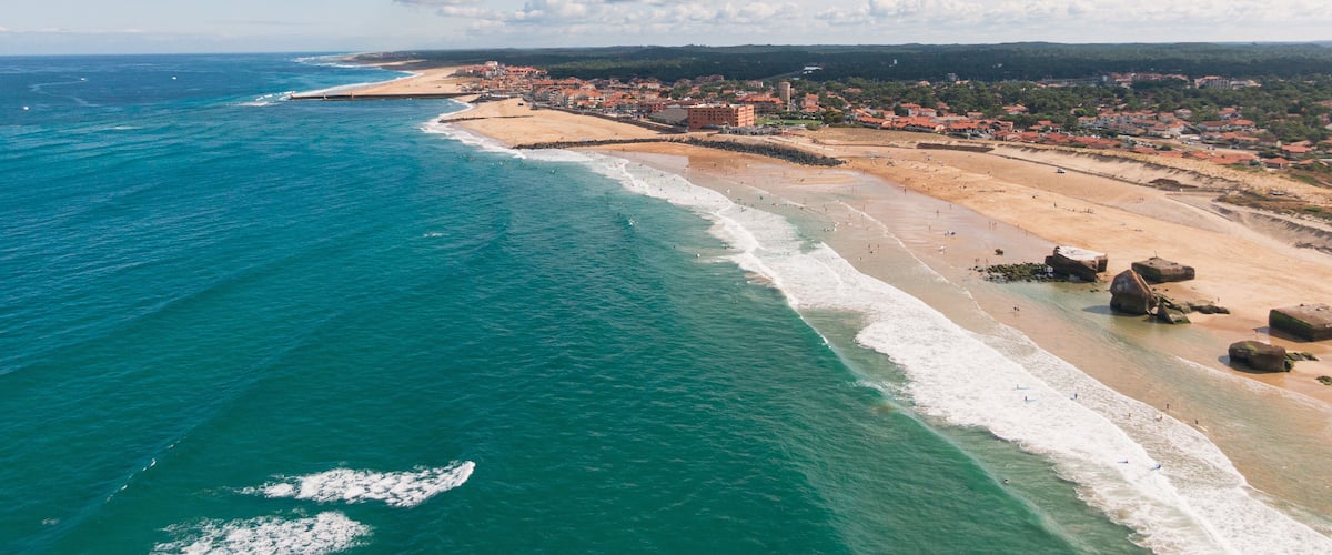 A coastal town with a beach, ocean, and a distant mountain range.