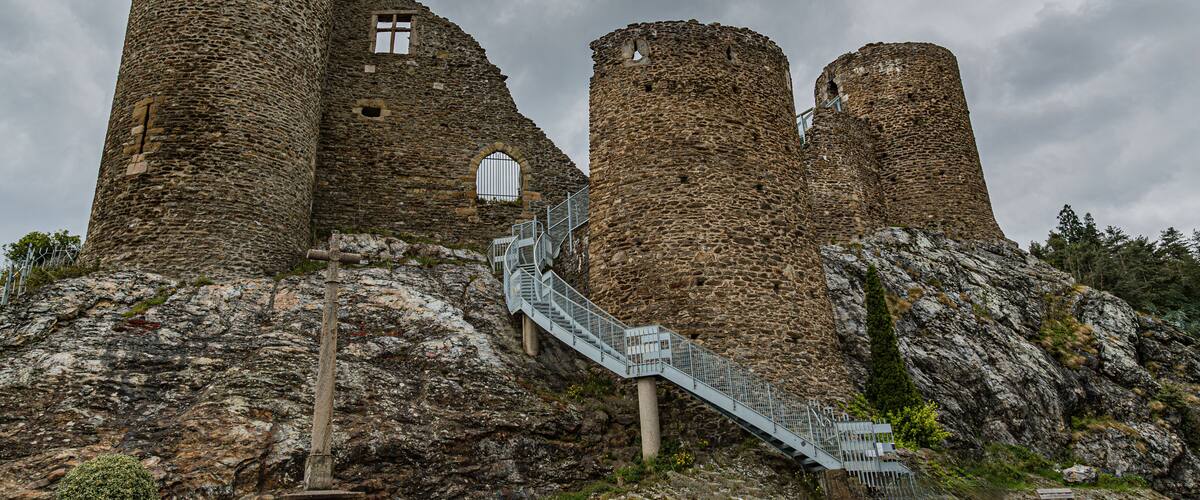 A historic stone castle with multiple towers and a staircase leading up to the entrance.