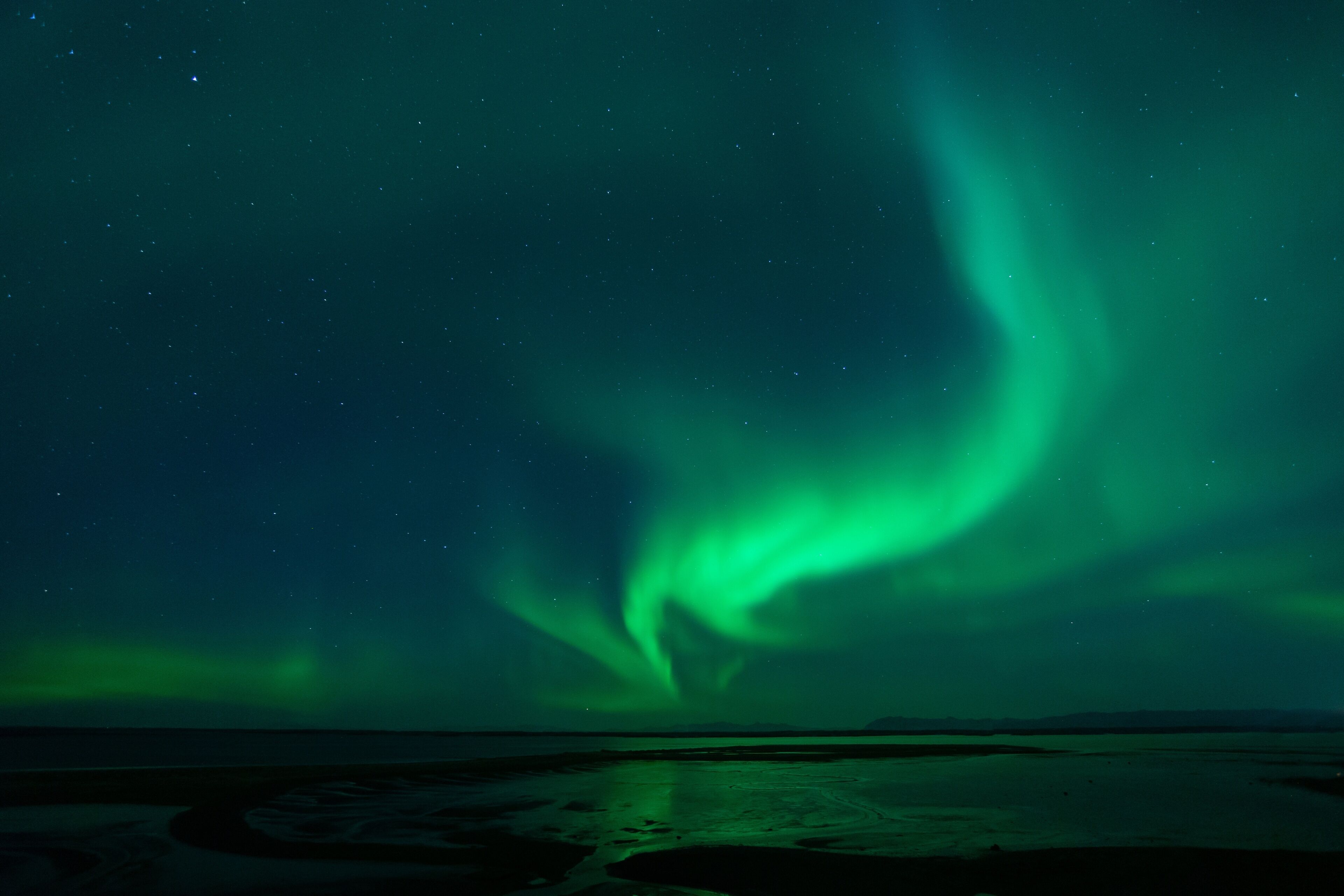 The Northern Lights over a coastal landscape.
