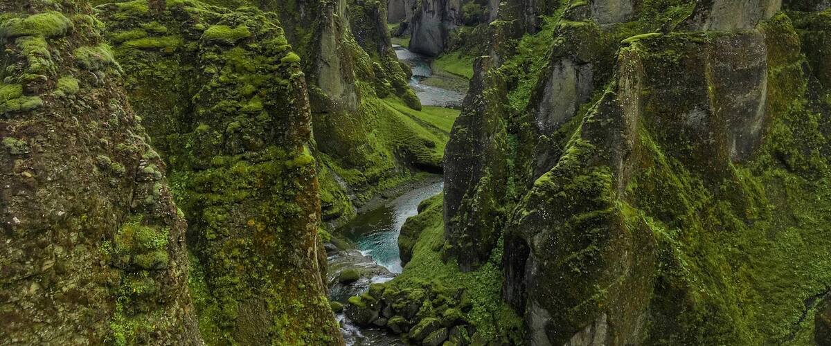 A river flowing through a canyon with green moss-covered cliffs.