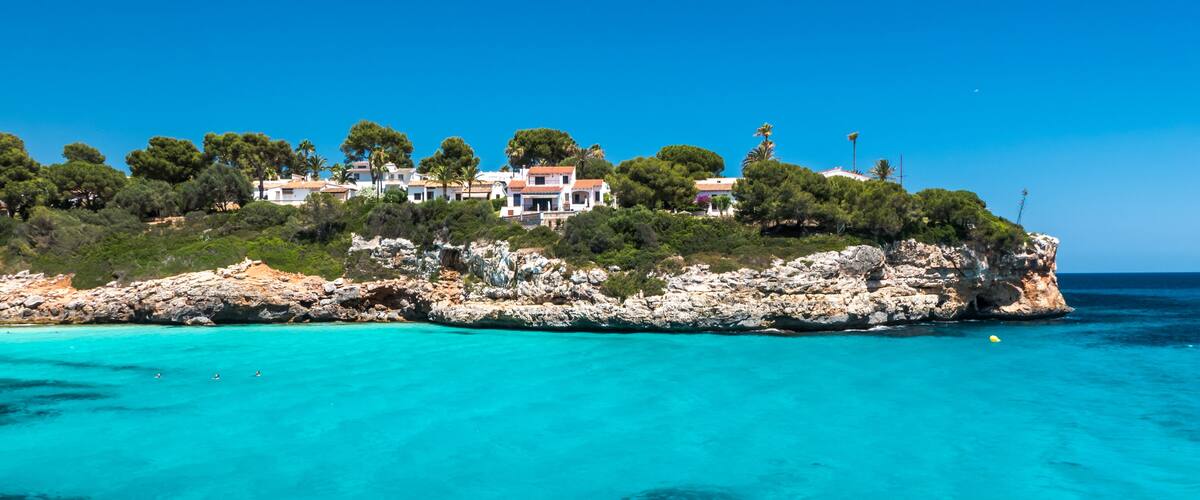 Un pueblo costero con casas sobre un acantilado rocoso, con vistas a aguas turquesas.