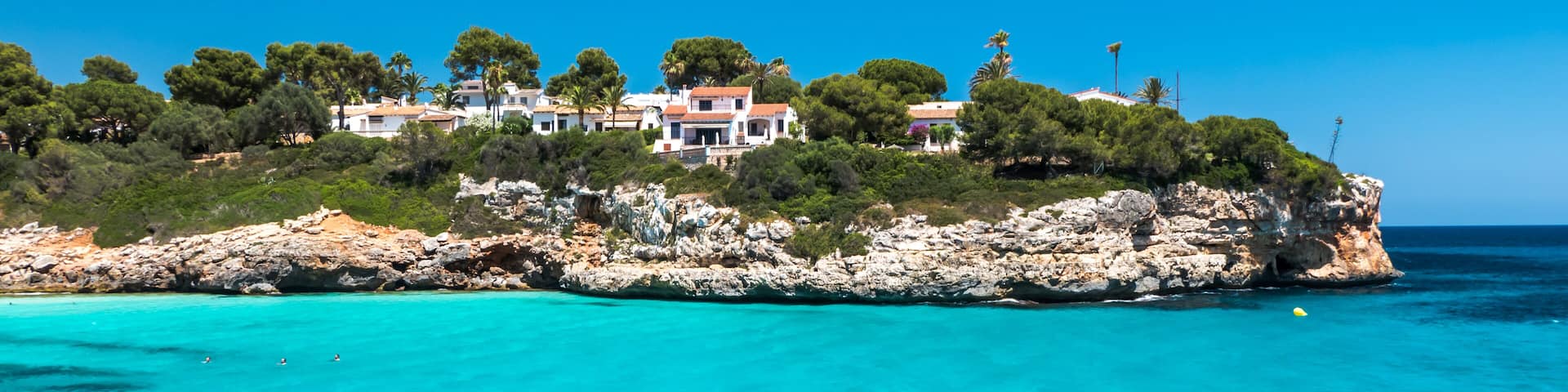 A coastal town with houses on a rocky cliff overlooking turquoise waters.