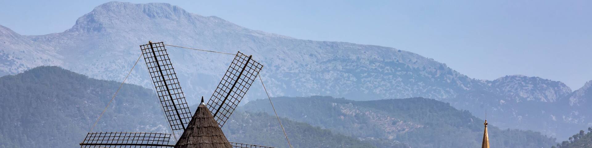 A windmill, a church, and mountains in the background.