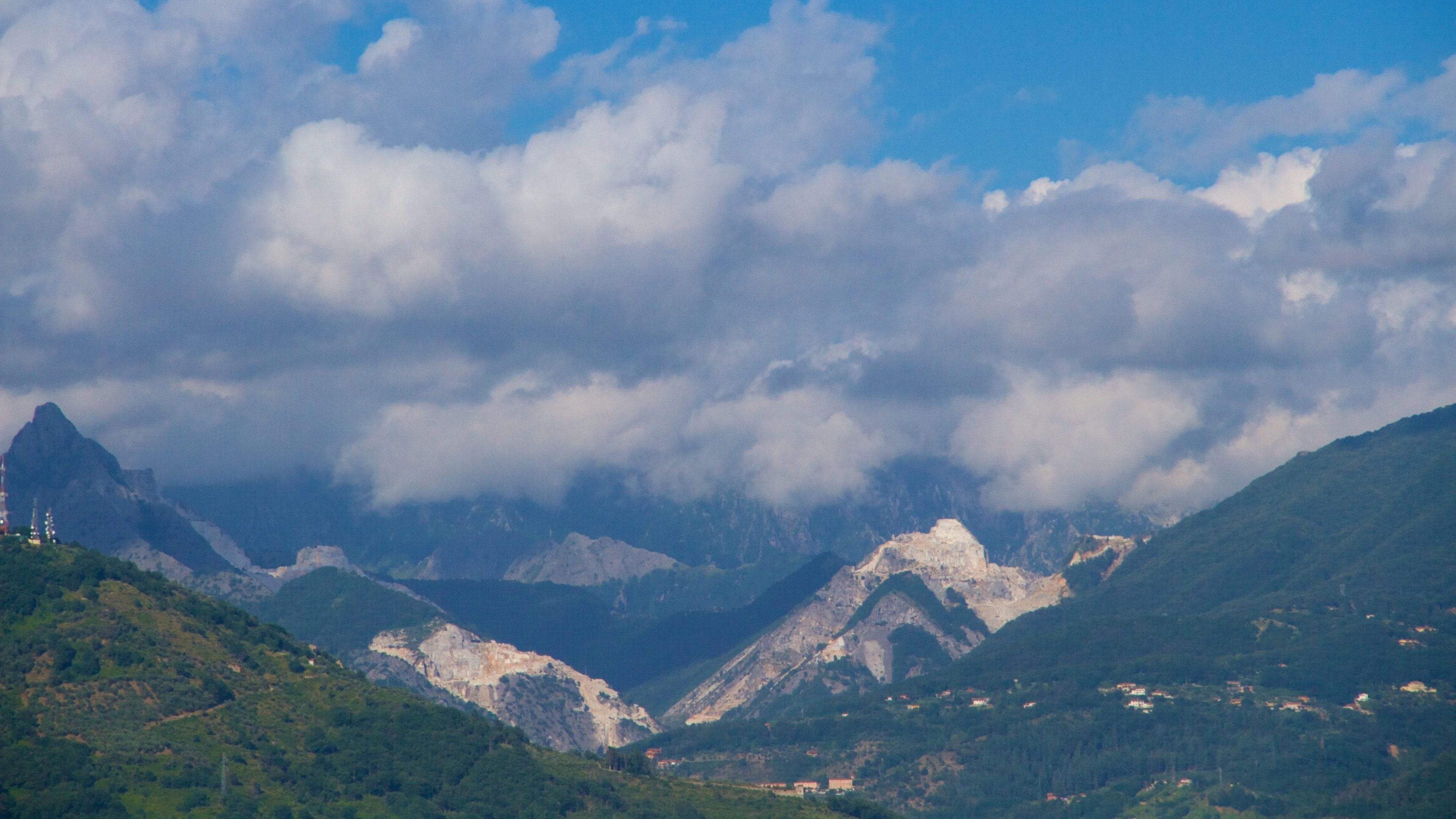 A mountainous landscape with a valley, scattered houses, and a prominent peak.