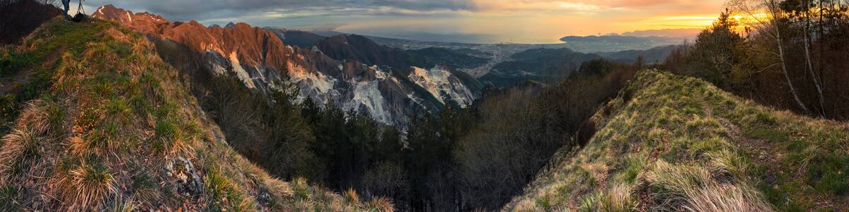 Un paysage montagneux avec une vallée, des falaises rocheuses et un coucher de soleil.