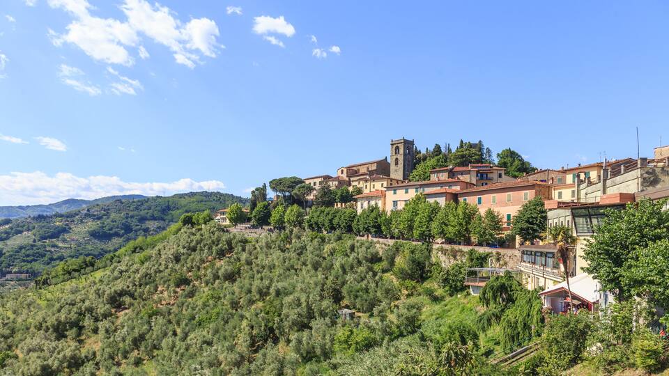 A hillside village with terraced houses, a church, and a prominent tower.