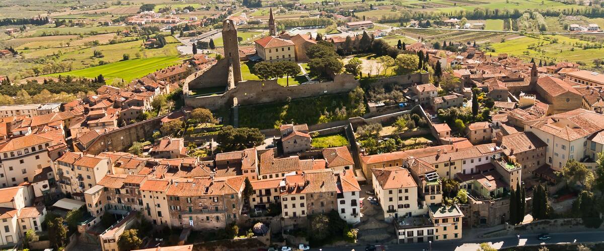 A historic town with a prominent church tower, surrounded by rolling hills and vineyards.
