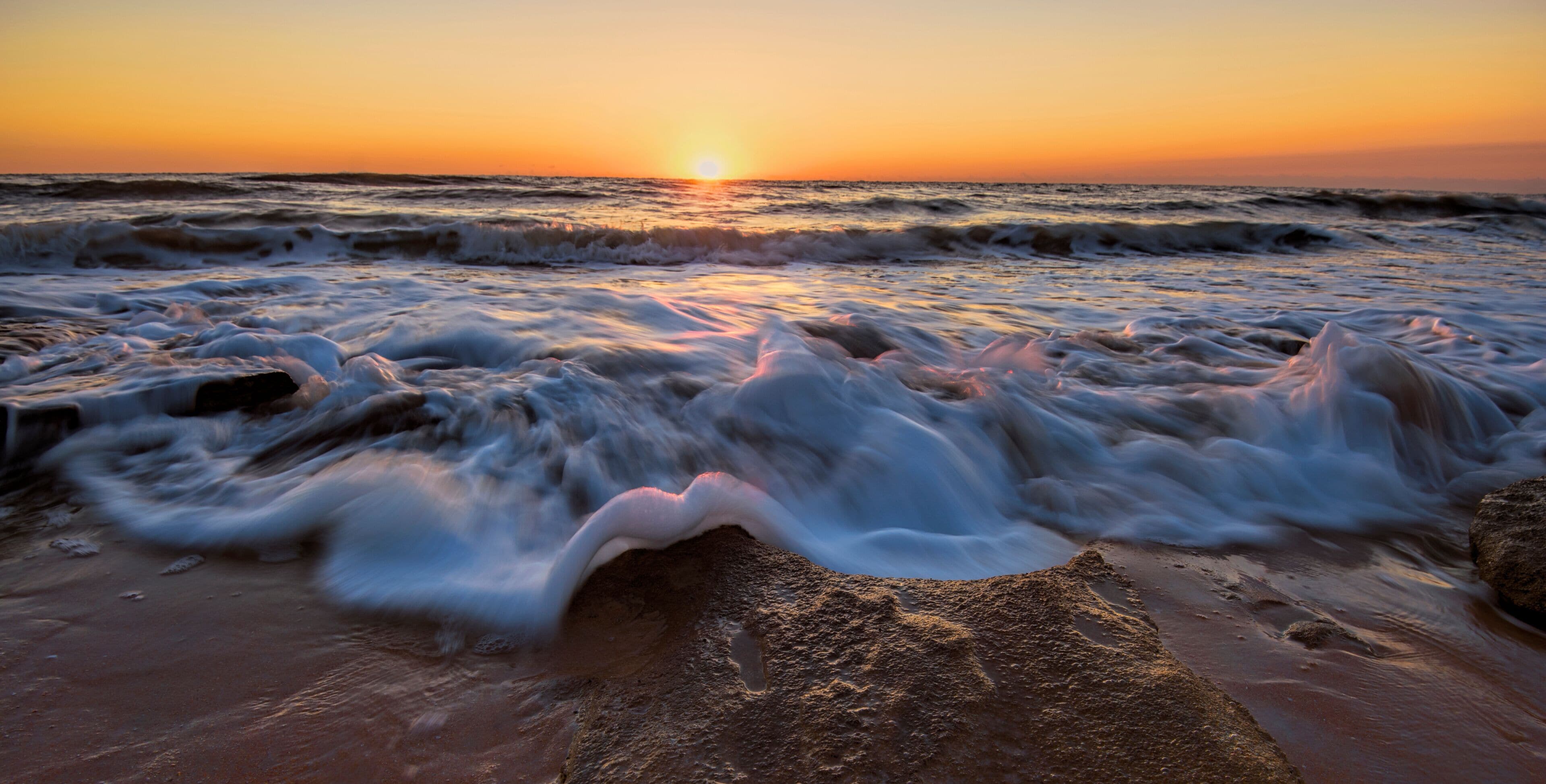 Una playa con olas al atardecer.