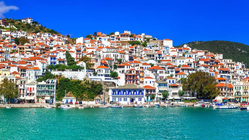A coastal town with colorful buildings, a clear blue sky, and a calm sea.