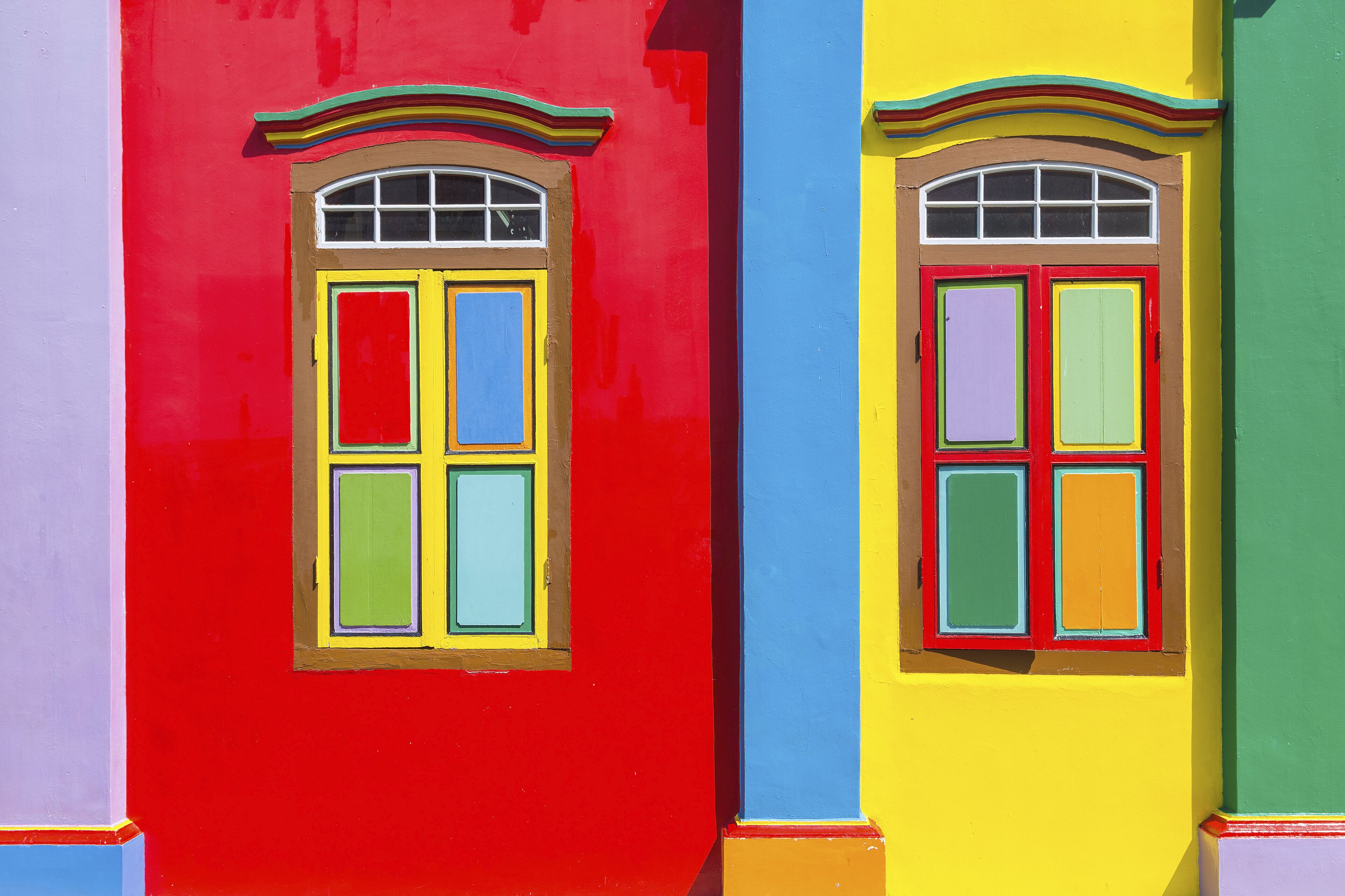 A row of colorful buildings with distinct red, yellow, and green facades and arched windows.