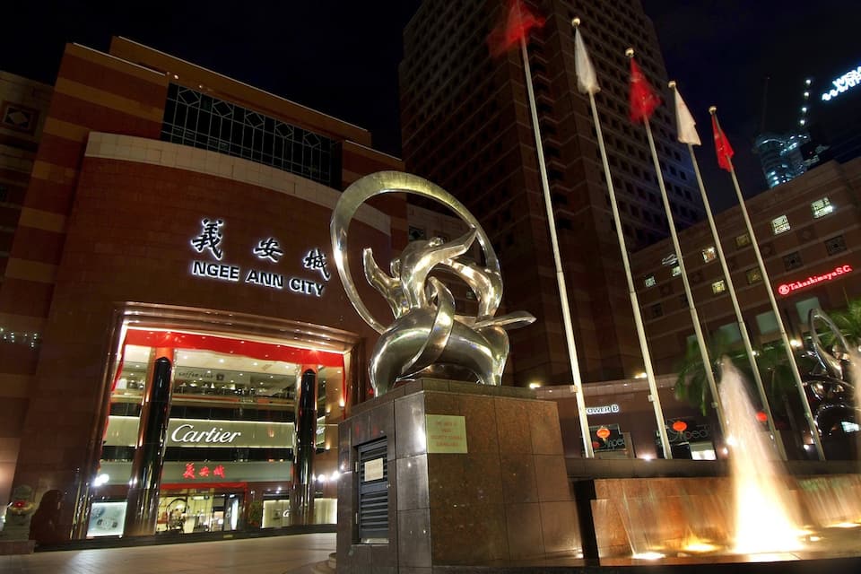 A modern building with a large sculpture in front, a Cartier store, and a sign for Ngee Ann City.