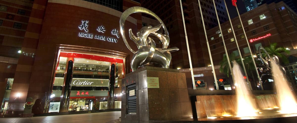 A modern building with a large sculpture in front, a Cartier store, and a sign for Ngee Ann City.