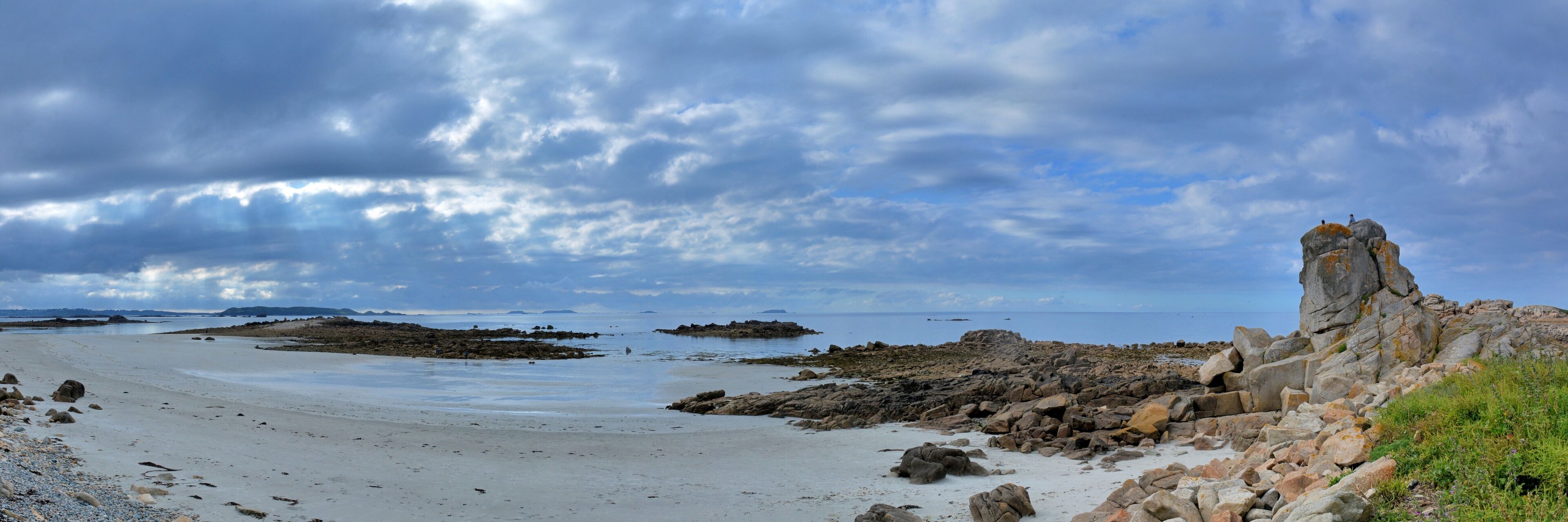 A rocky beach with a prominent rock formation on the right.