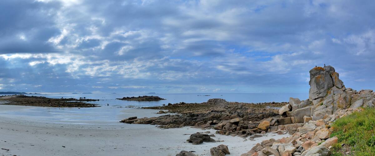 A rocky beach with a prominent rock formation on the right.