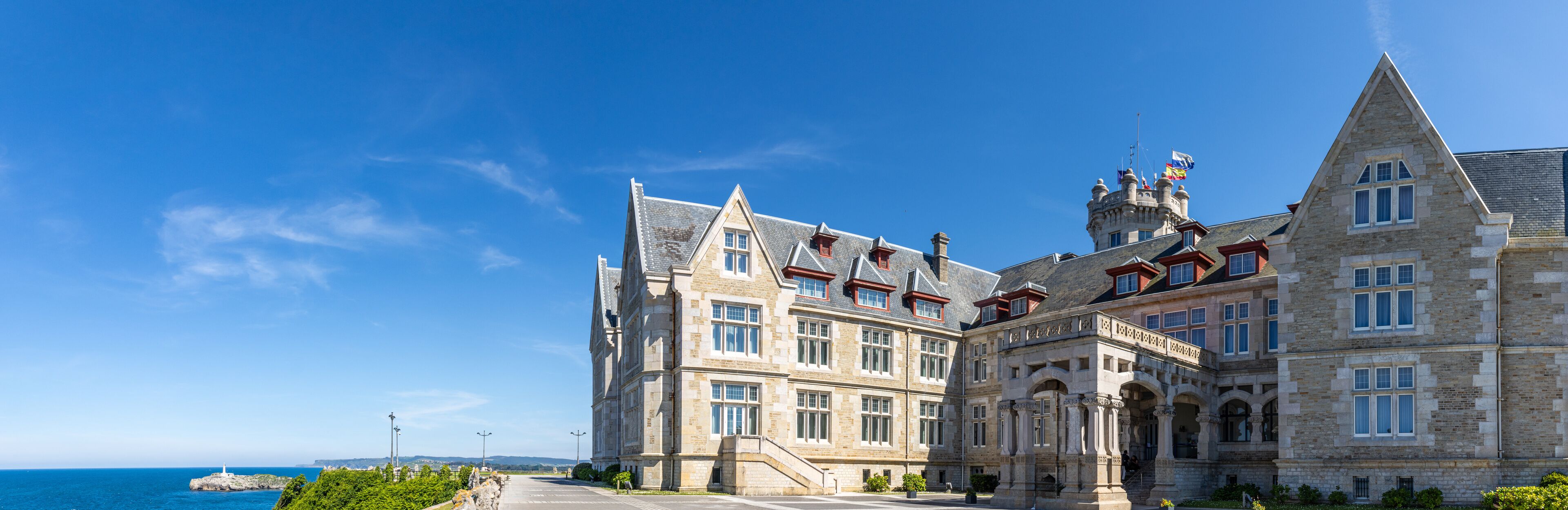Un edificio histórico de piedra con múltiples torres y vistas al mar.