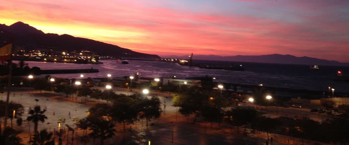 A sunset over a coastal city with mountains in the background.