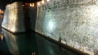 A fortified wall with a moat at night.