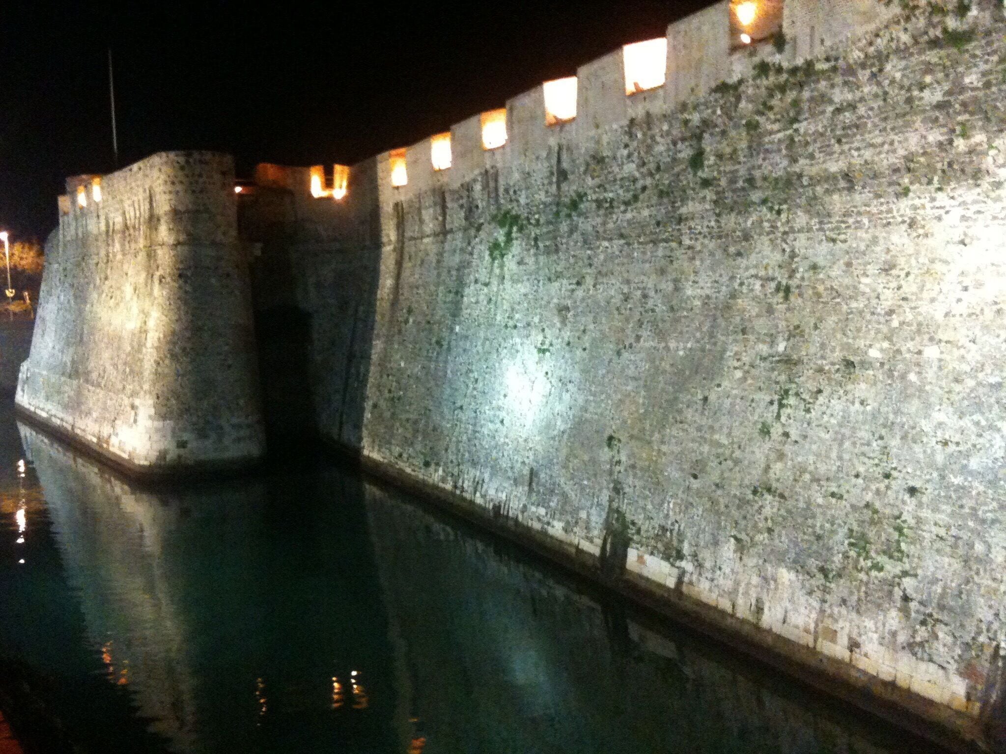 A fortified wall with a moat at night.