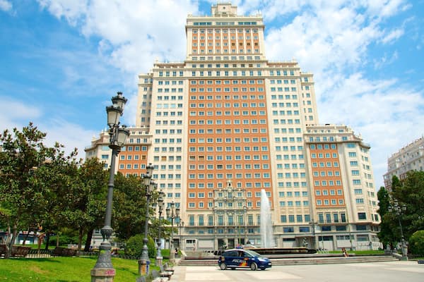 A large, multi-story building with a central fountain and surrounding greenery.