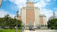 A large, multi-story building with a central fountain and surrounding greenery.